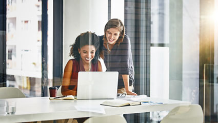 Woman lookin over should of another woman using laptop