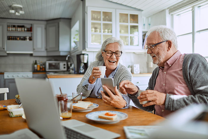 Retired couple viewing Smartphone at kitchen table
