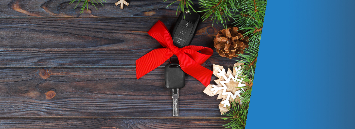 Car key with red bow on wood background