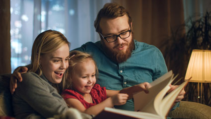 Young couple reading book with child