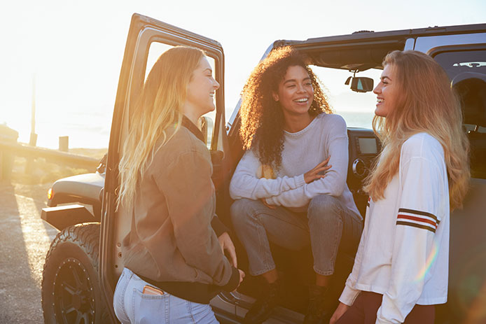 Three young women talking by vehicle