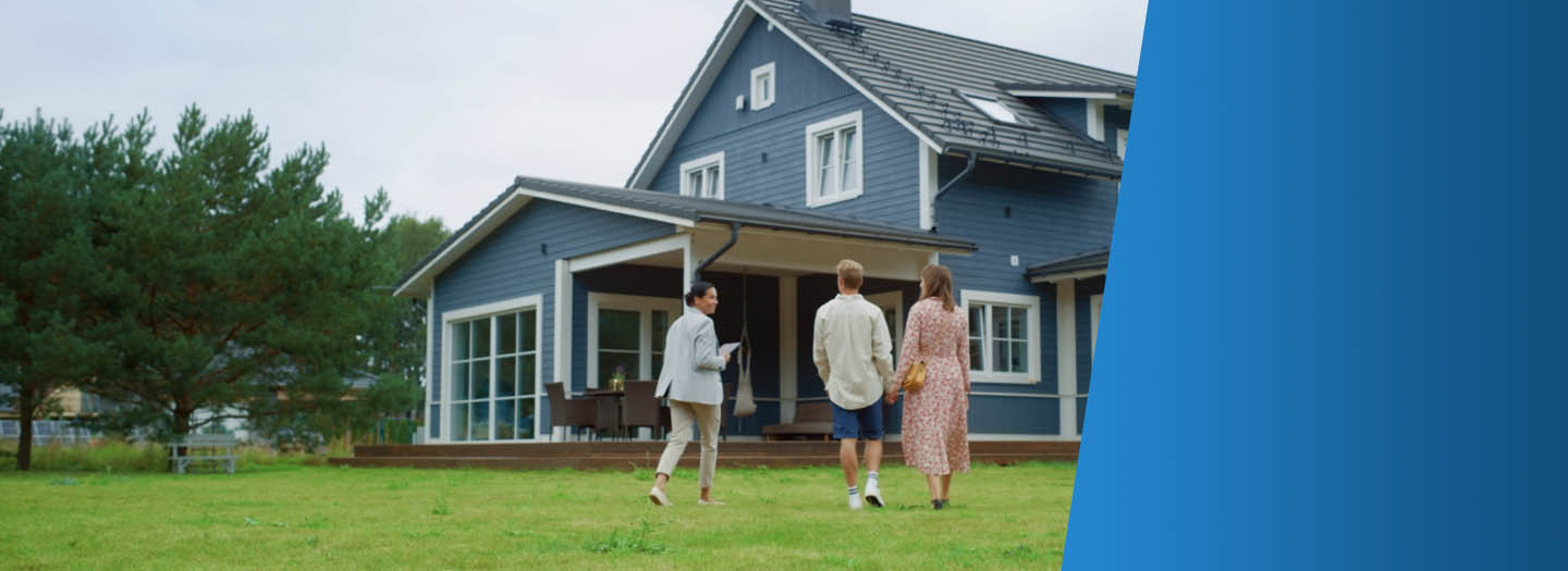 A couple and realtor walking towards a blue house with white trim