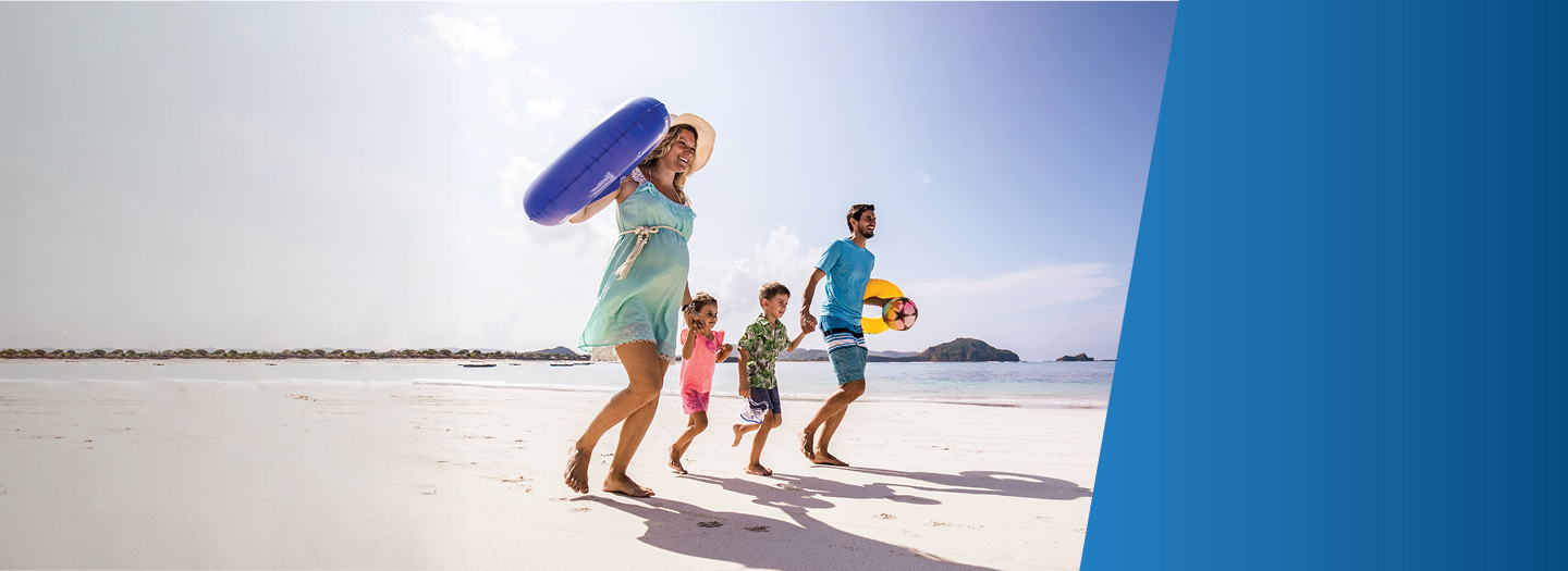Family of four holding hands running on the beach