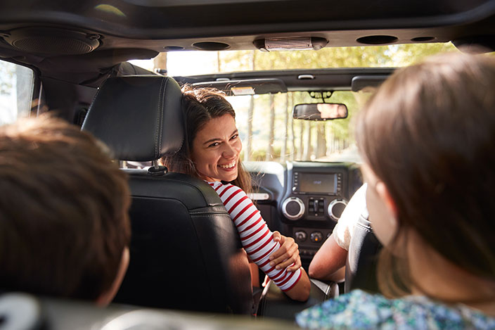 Mom in front seat of car talking to kids in back seat