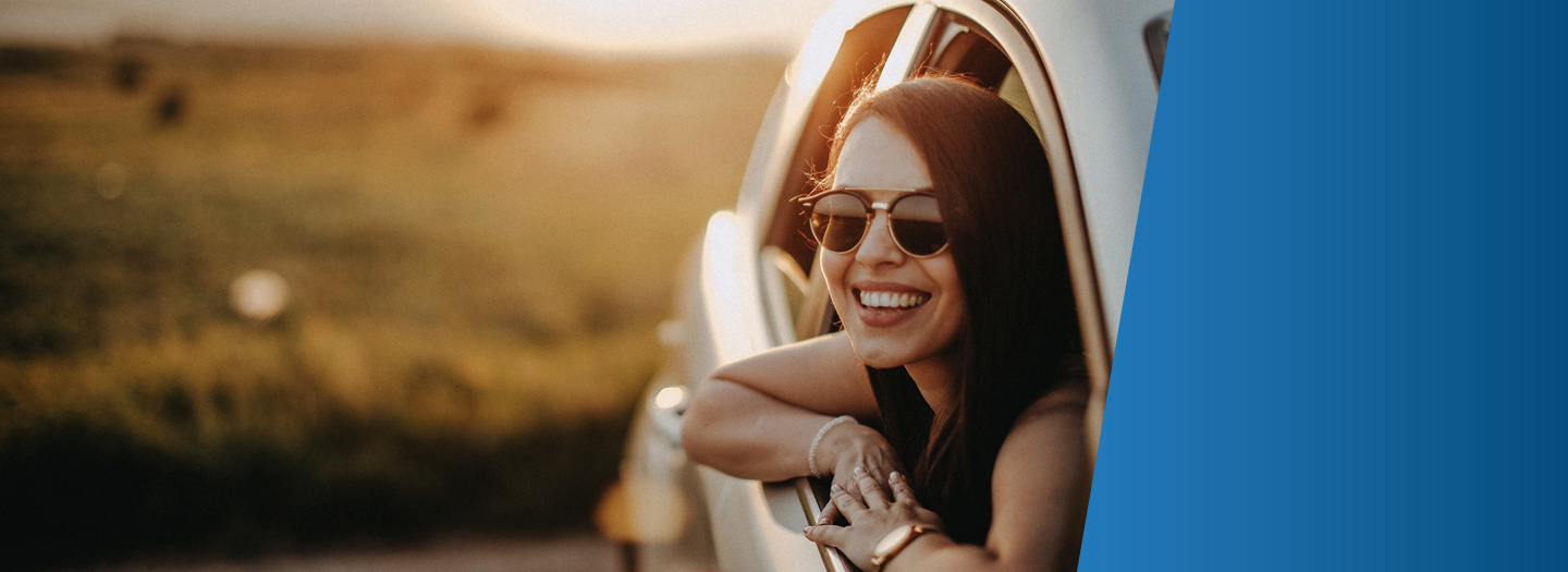 Woman wearing sunglasses leaning out of car window