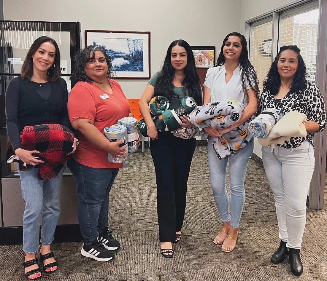 Five EECU employees, each holding multiple blankets that are being donated to Fresno shelter animals 